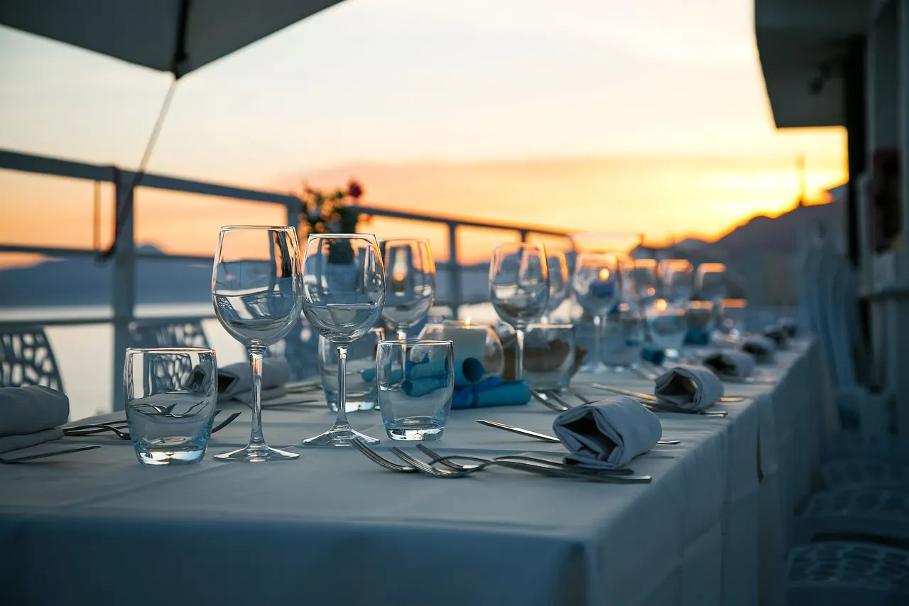 Gedekte tafel met wijnglazen op een terras aan zee bij zonsondergang