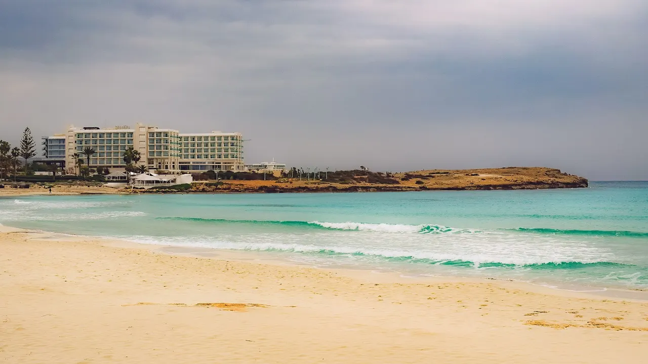 Breed zandstrand met turquoise zee en een groot hotel aan de kust bij Ayia Napa