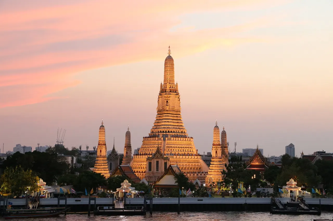 Wat Arun aan de Chao Phraya-rivier in Bangkok bij zonsondergang met roze lucht