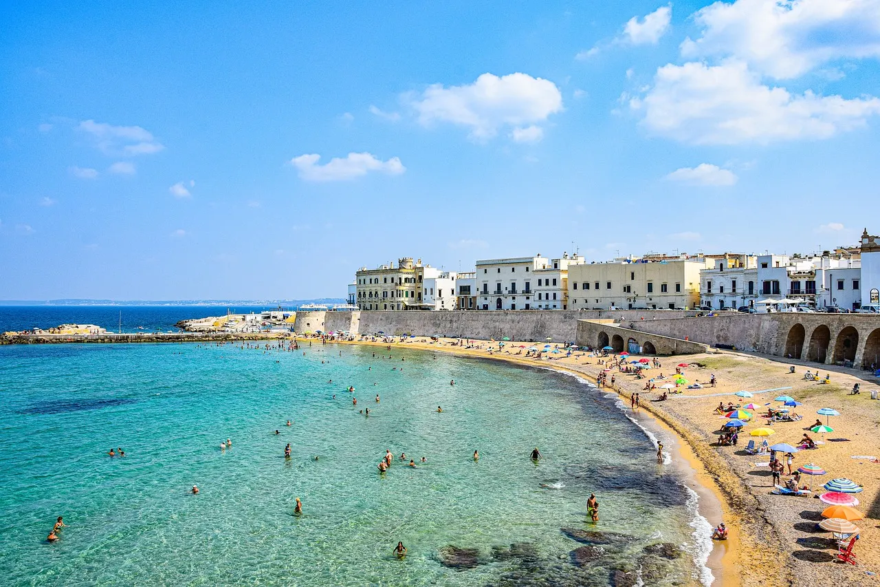 Spiaggia della Purità in Gallipoli met helderblauw water, zandstrand en witte huizen op de stadsmuur