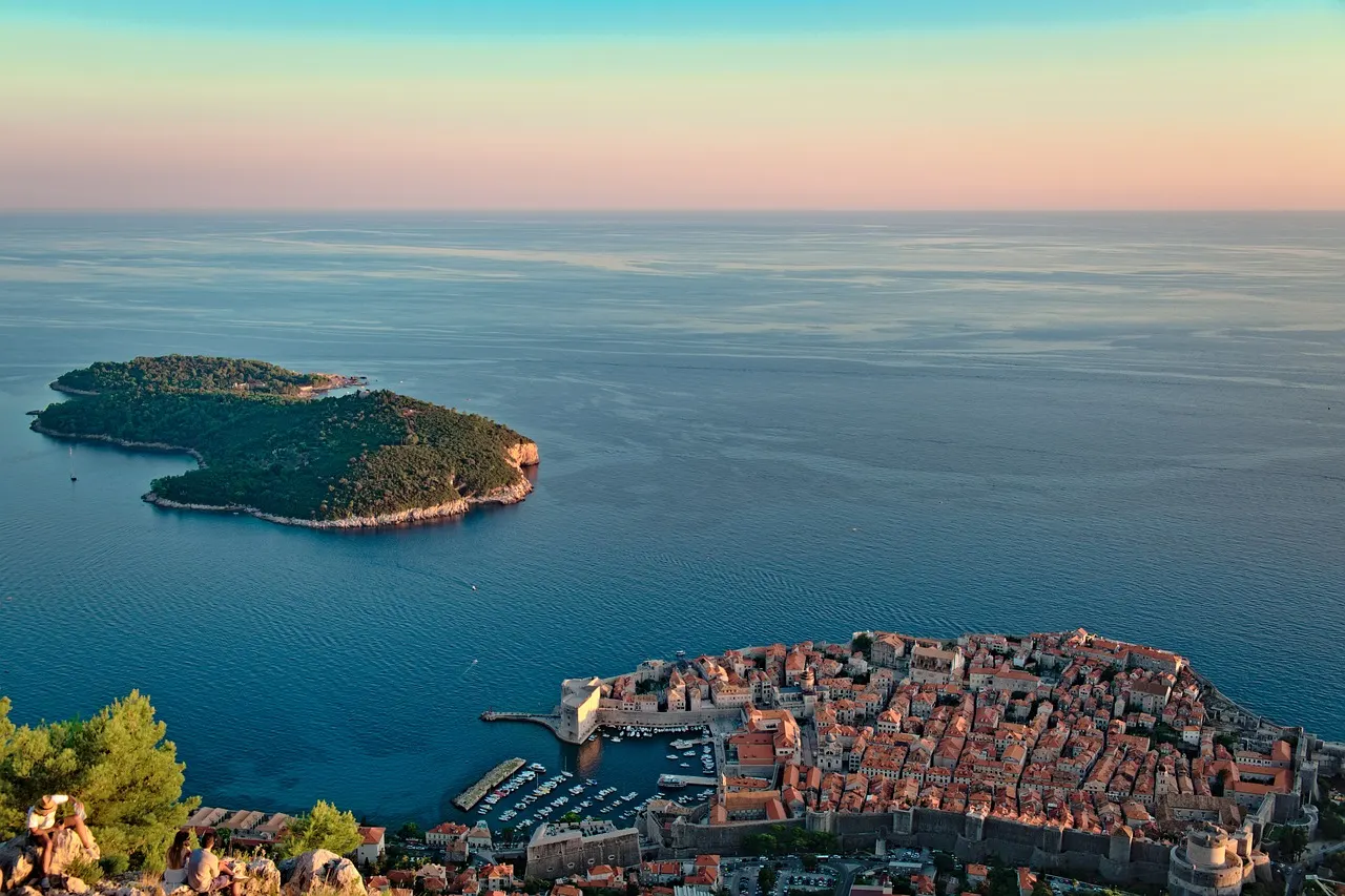 Luchtfoto van het beboste eiland Lokrum met rotsige kust in blauwe zee, naast de oude stad van Dubrovnik