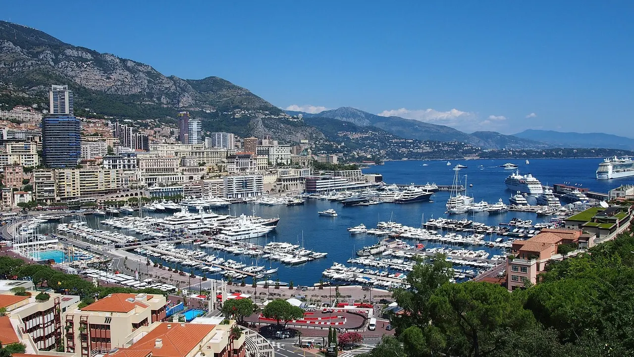 Uitzicht over de haven van Monte Carlo met jachten, blauwe zee en de stad tegen de bergen