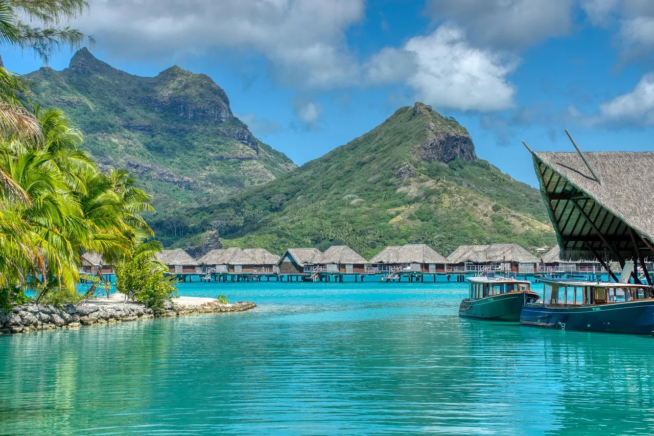 Turquoise lagune met overwaterbungalows, boten en groene bergtoppen van Bora Bora op de achtergrond