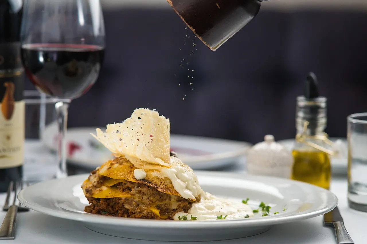 Verfijnd Italiaans gerecht met krokante kaas op een wit bord, met rode wijn en olijfolie op tafel