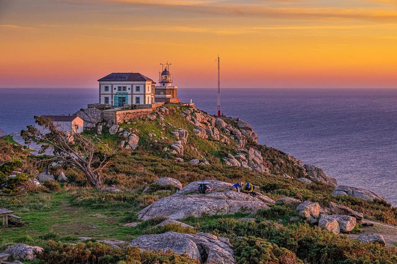 Vuurtoren van Finisterre op een rotsachtige kaap boven de oceaan bij zonsondergang in Galicië