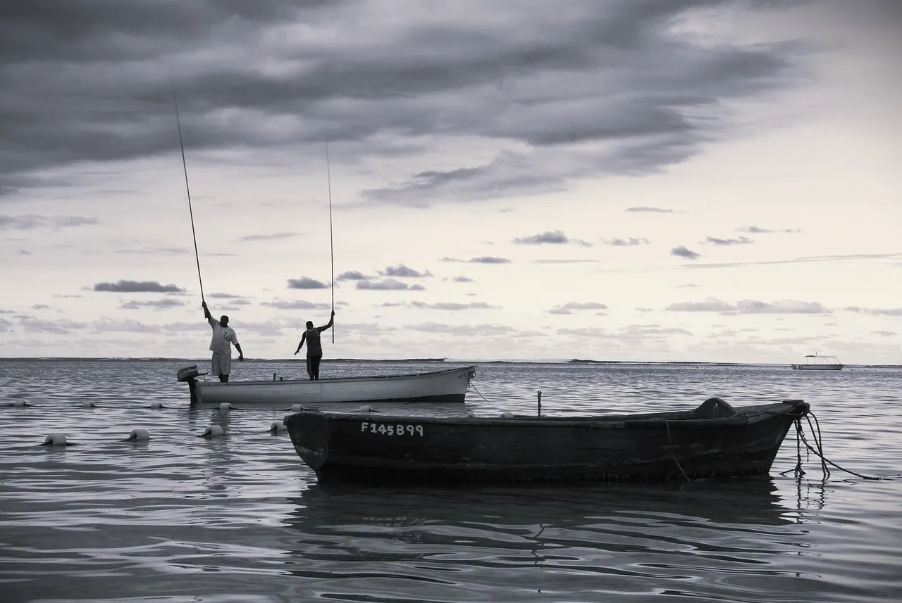 Vissersboten in ondiep lagunewater onder bewolkte lucht, zwart-witfoto aan de kust van Mauritius