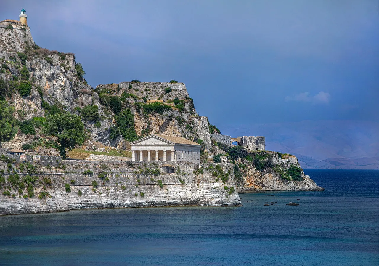 Oude vesting van Corfu-stad met de tempel van Sint-Joris aan de rotsachtige kust en blauwe zee