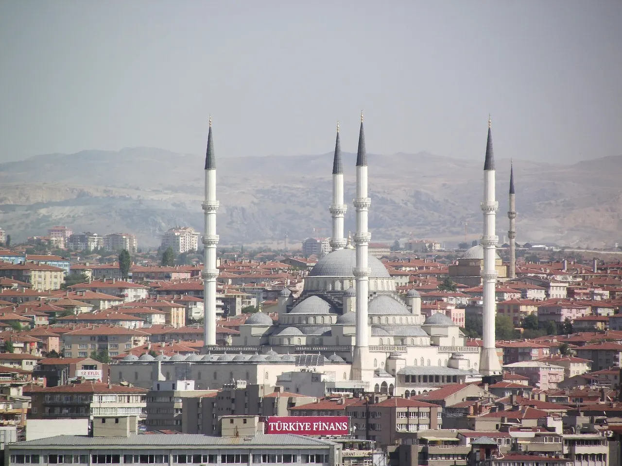 De Kocatepe-moskee met vier minaretten tussen de huizen van Ankara, met heuvels op de achtergrond