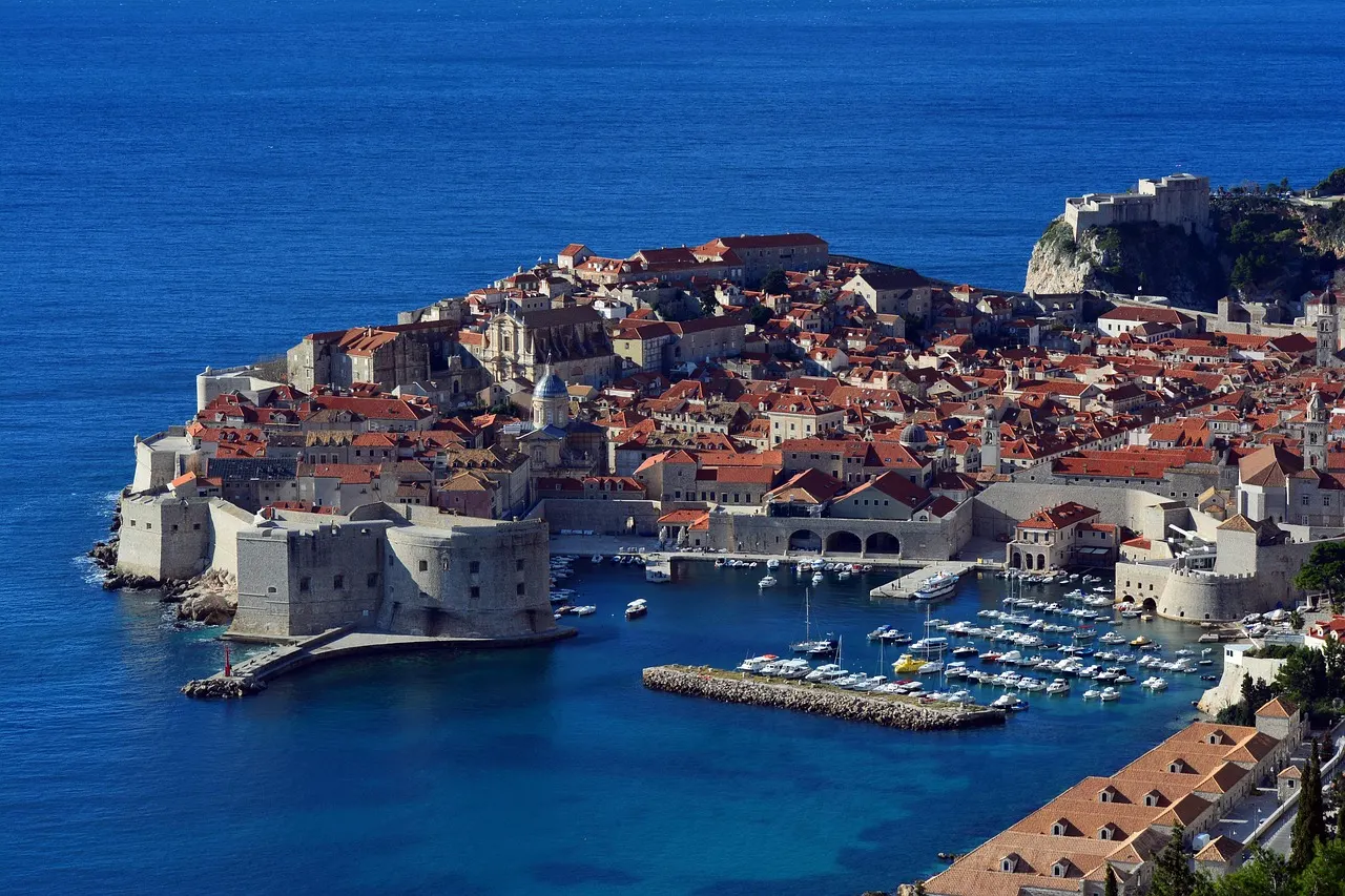 Uitzicht op de ommuurde oude stad van Dubrovnik met haven, Fort Sint-Jan en Fort Lovrijenac aan zee