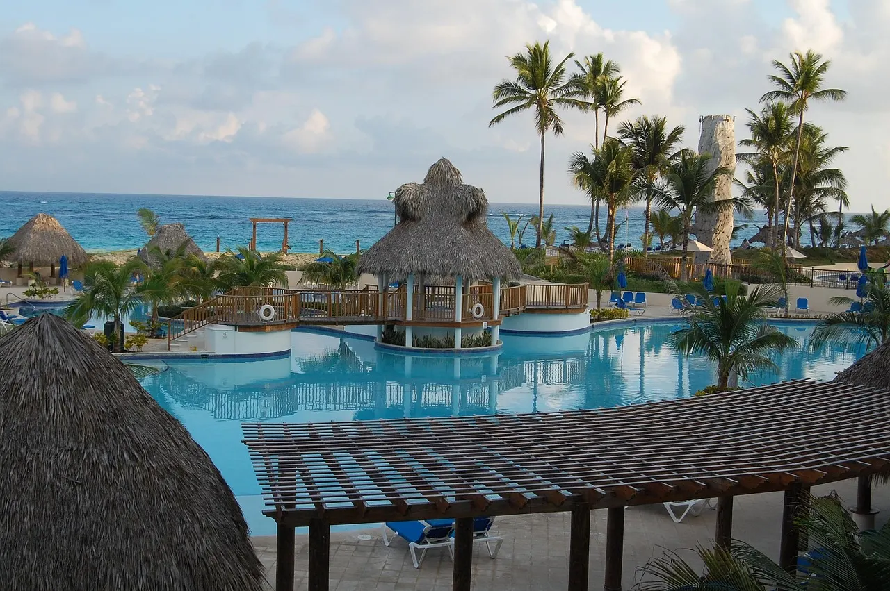 Zwembad met rieten parasols en palmbomen bij een resort aan de Caribische Zee in Punta Cana