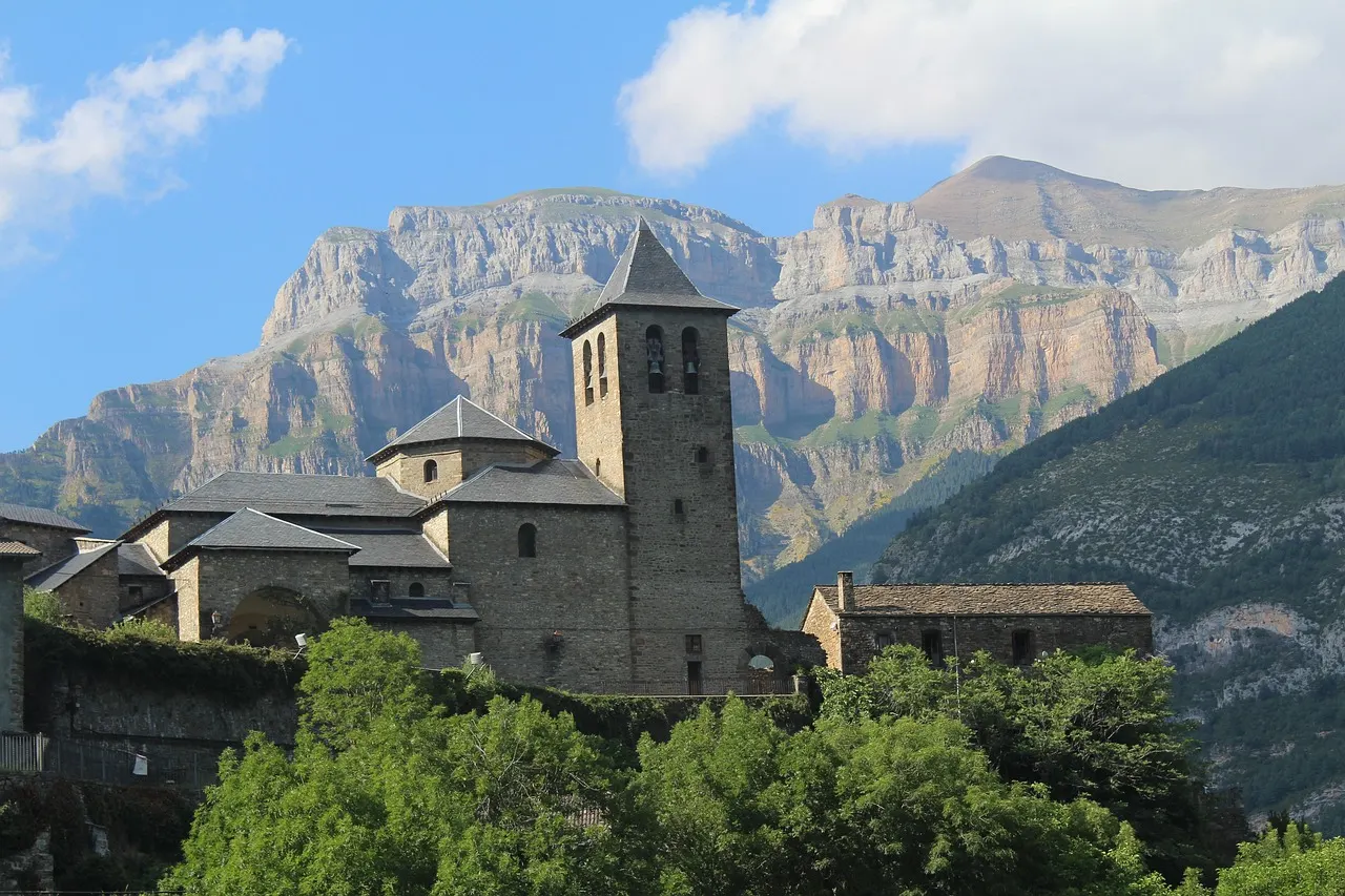 Romaanse kerk van Torla met daarachter de steile kalkstenen bergwanden van de Spaanse Pyreneeën