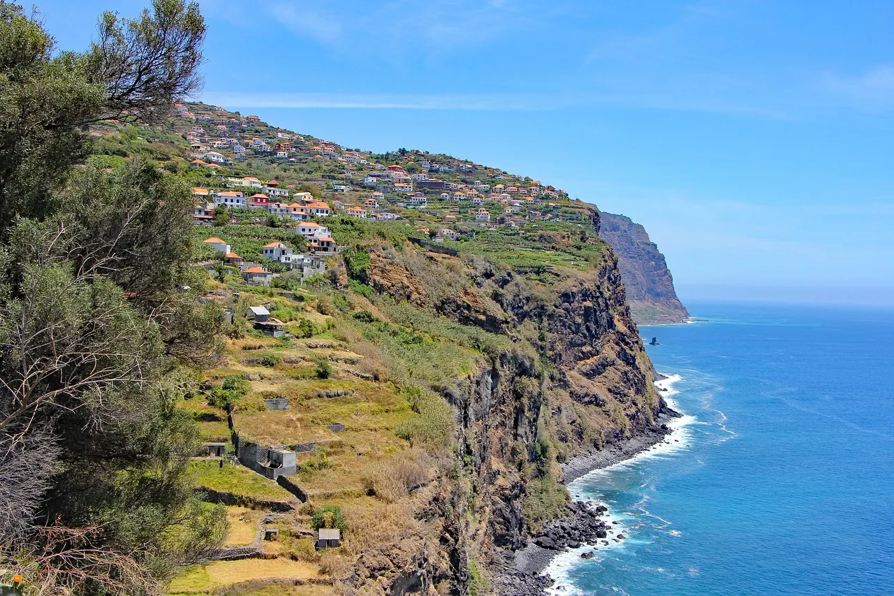 Groene terrassen en huizen op steile kliffen langs de blauwe oceaan aan de kust van Madeira
