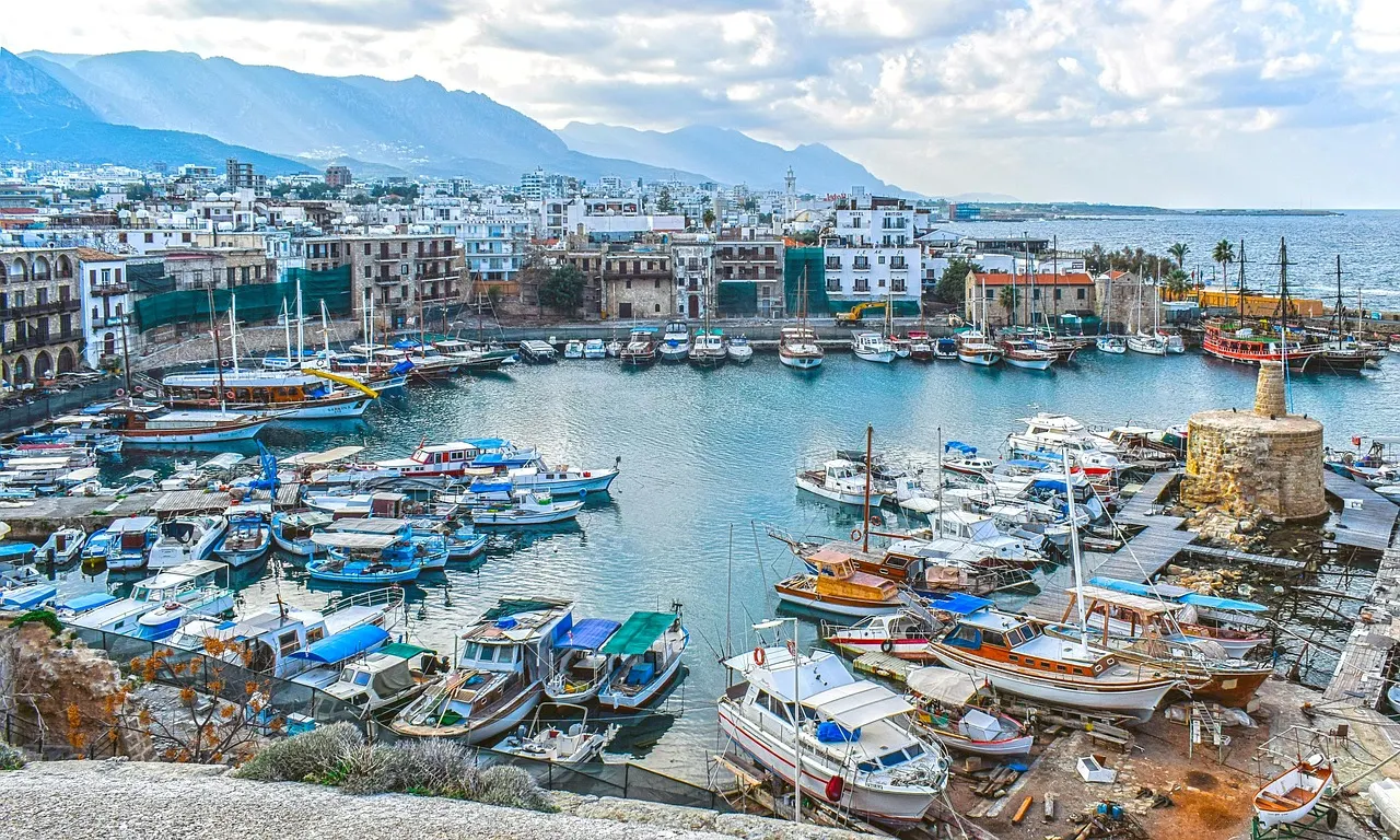 Uitzicht over de hoefijzervormige haven van Kyrenia met vissersboten, oude gebouwen en bergen op de achtergrond