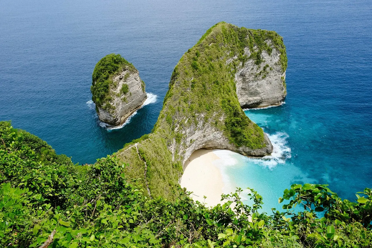 Kelingking Beach op Nusa Penida: groene T-vormige klif boven een wit strand en turquoise zee