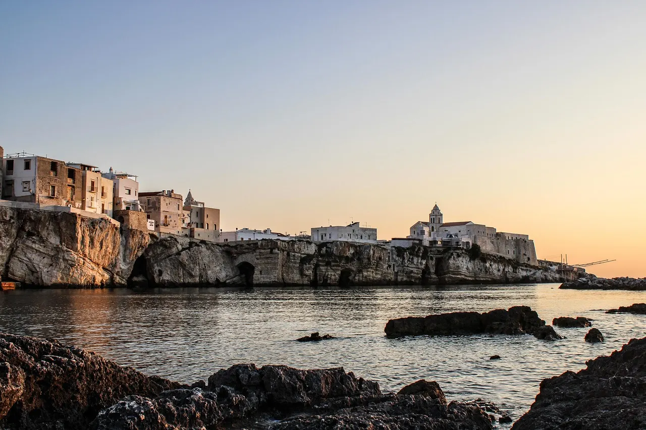 Witte huizen van Vieste op kalkrotsen boven zee bij zonsondergang aan de kust van Gargano