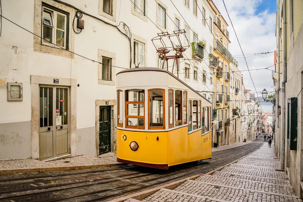 Gele kabeltram Elevador da Bica rijdt door een steile smalle straat in Lissabon