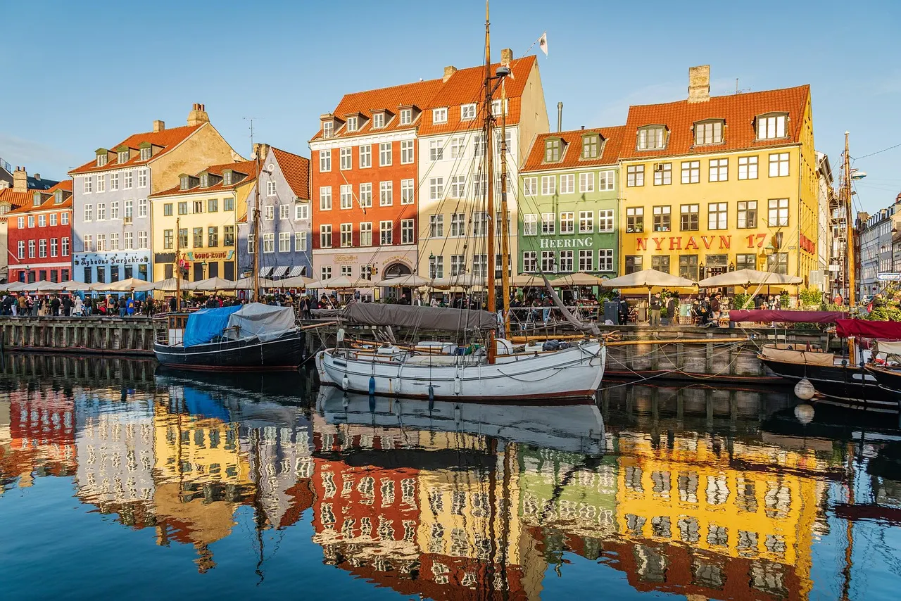 Kleurrijke gevels en houten zeilboten weerspiegeld in het water van de Nyhavn in Kopenhagen