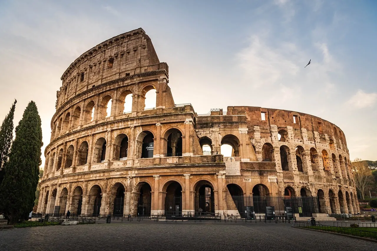 Het Colosseum in Rome bij zonsopkomst, met cipressen en een zachte lucht