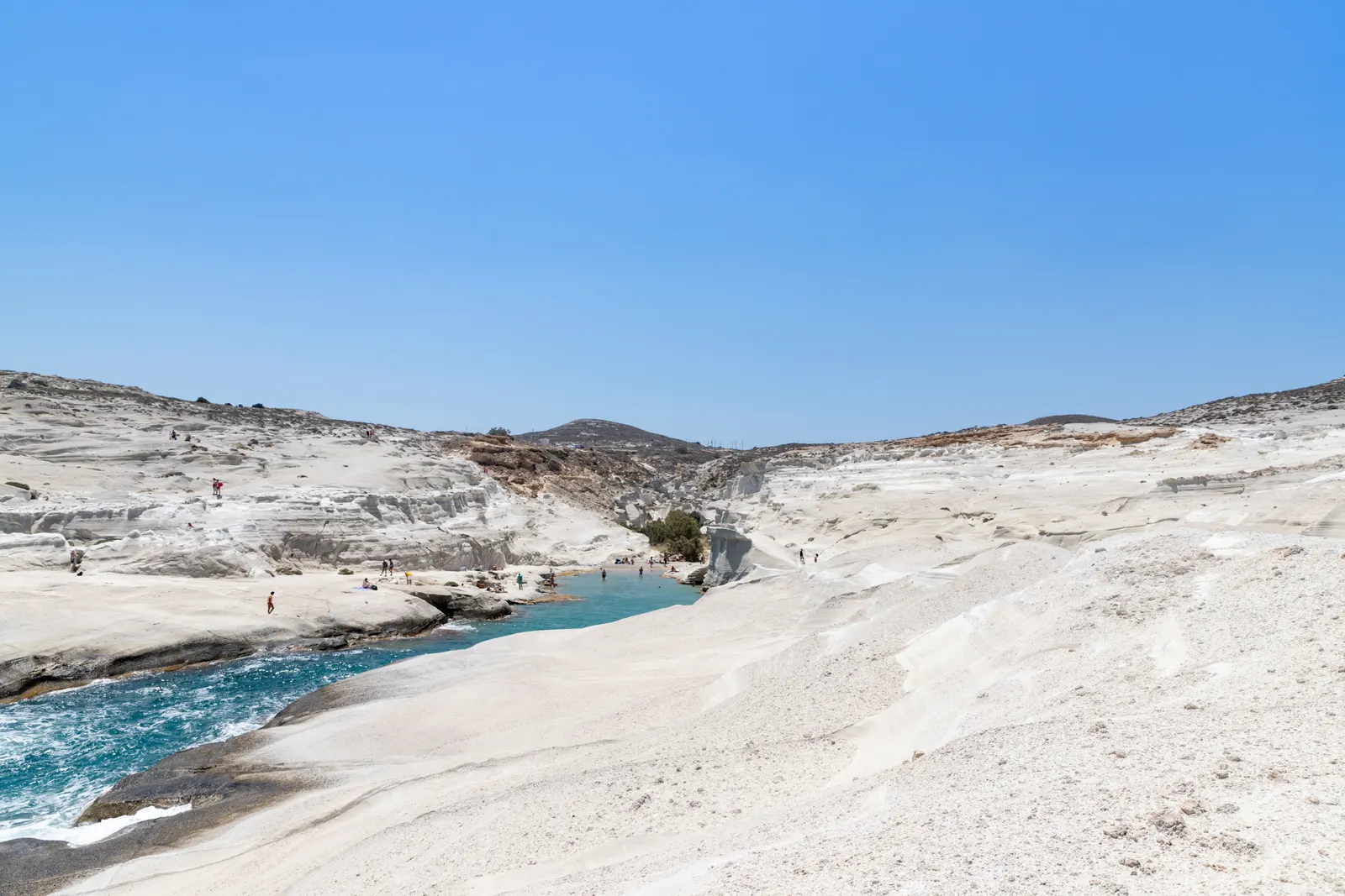 Witte, gladde rotsen van Sarakiniko met een smalle turquoise baai onder een strakblauwe lucht op Milos