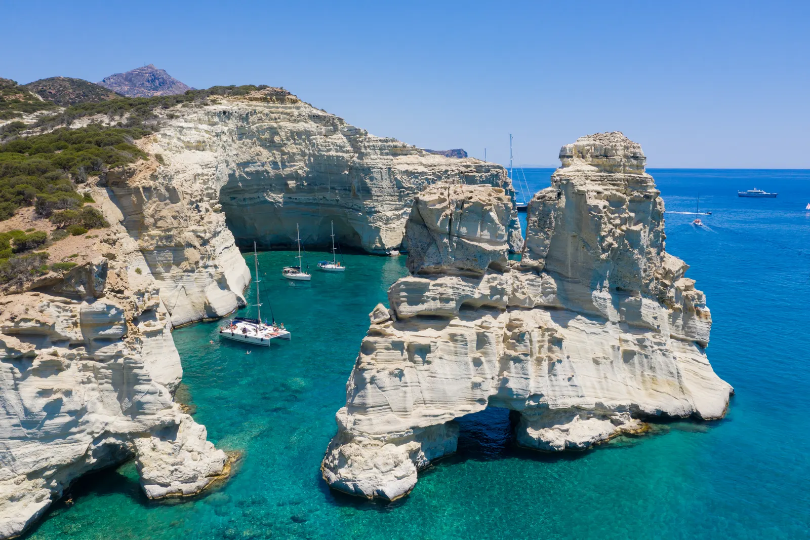 Luchtfoto van de witte rotsformaties en turquoise baai van Kleftiko op Milos met zeilboten