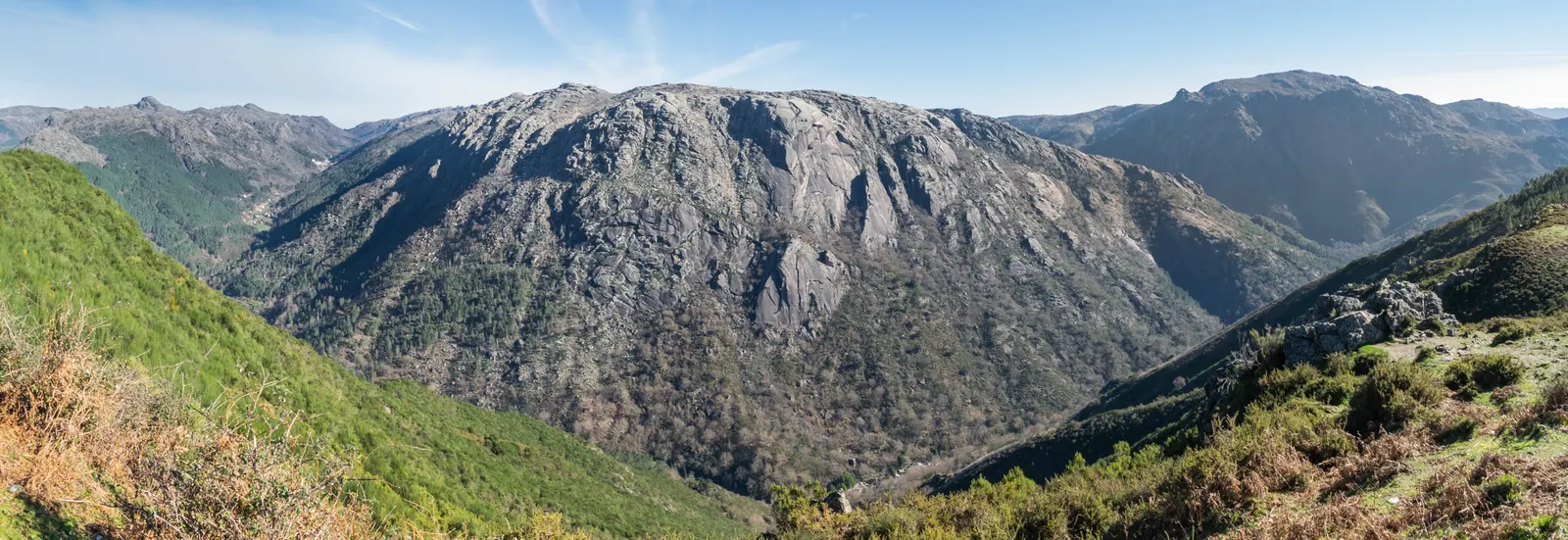 Ruige granieten bergen en groene, beboste valleien in Nationaal Park Peneda-Gerês onder een blauwe lucht