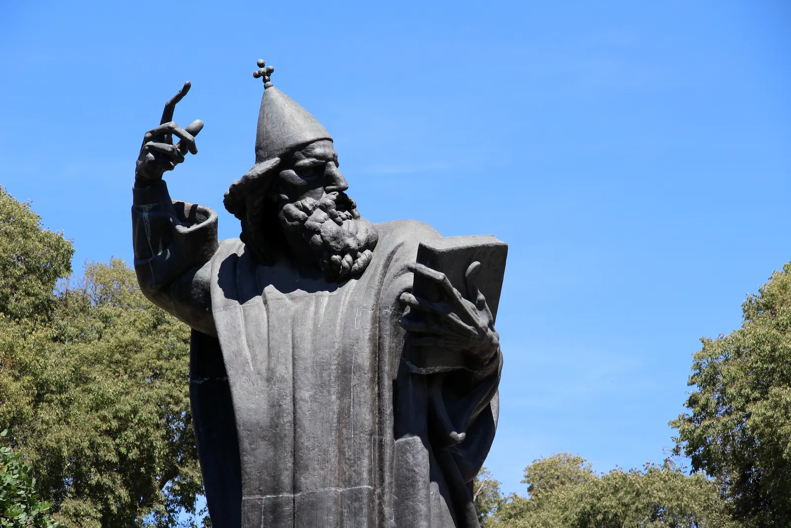 Bronzen beeld van Grgur Ninski met opgeheven hand en boek tegen een strakblauwe lucht in Split