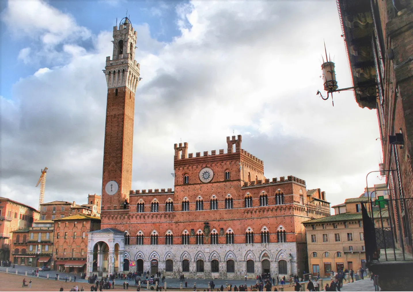 Het Palazzo Pubblico met de slanke Torre del Mangia aan het Piazza del Campo in Siena onder een wolkenlucht