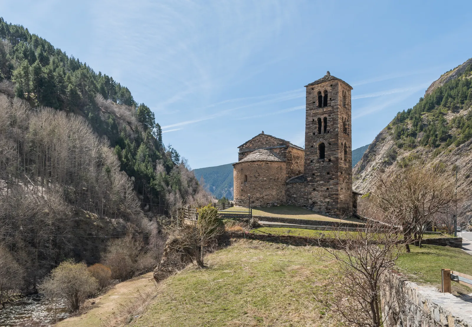 Romaanse kerk Sant Joan de Caselles met stenen klokkentoren in een bergdal onder blauwe lucht