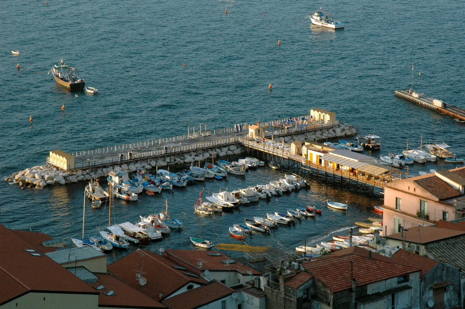 Uitzicht op het haventje Marina Grande in Sorrento met vissersboten, een pier en rode daken