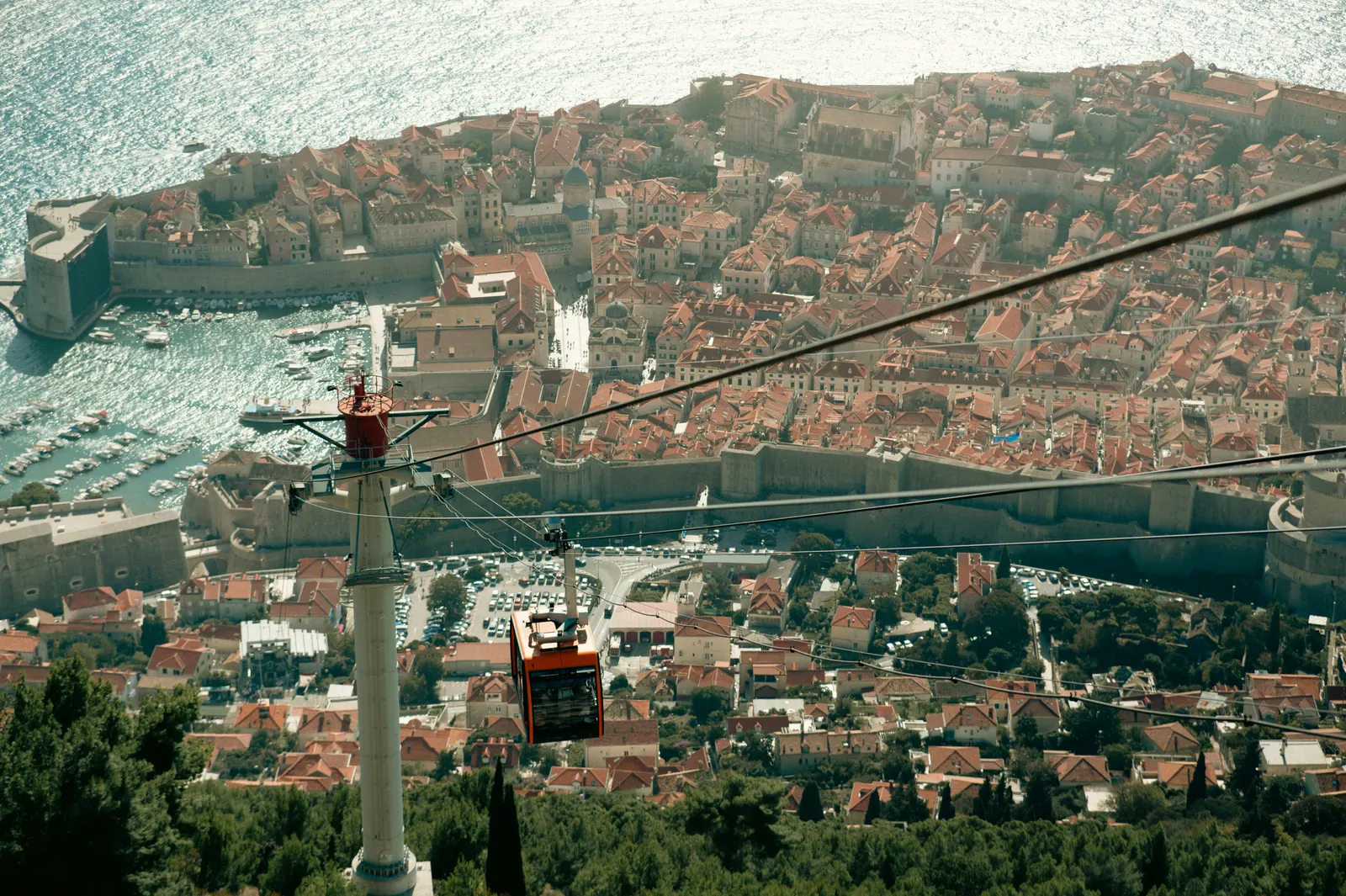 Rode cabine van de kabelbaan boven de daken en stadsmuren van de oude stad van Dubrovnik