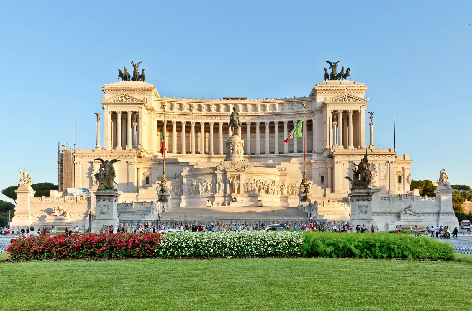 Het witte marmeren Vittoriano-monument in Rome met ruiterstandbeeld en bloemperken in warm avondlicht