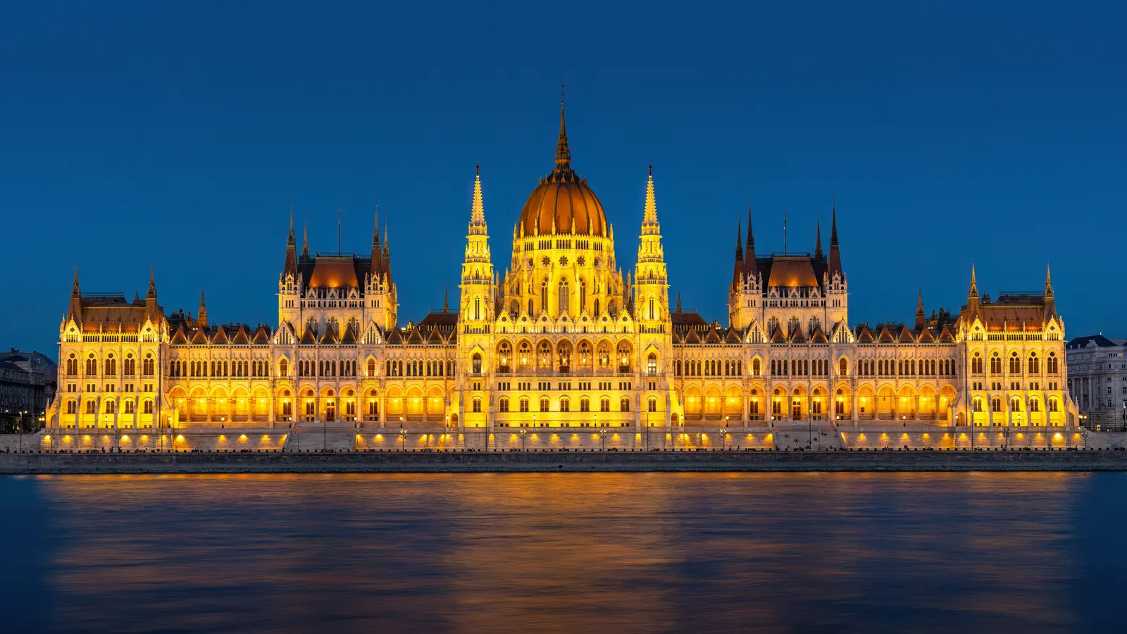 Verlicht Parlementsgebouw van Boedapest aan de Donau tijdens het blauwe uur, weerspiegeld in het water