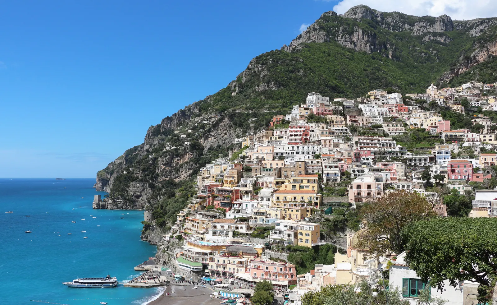 Kleurrijke huizen van Positano tegen de steile kliffen boven de blauwe zee aan de Amalfikust