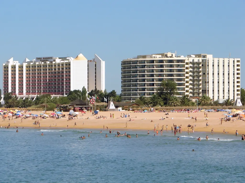 Zandstrand van Vilamoura met badgasten, parasols en grote witte hotels op de achtergrond