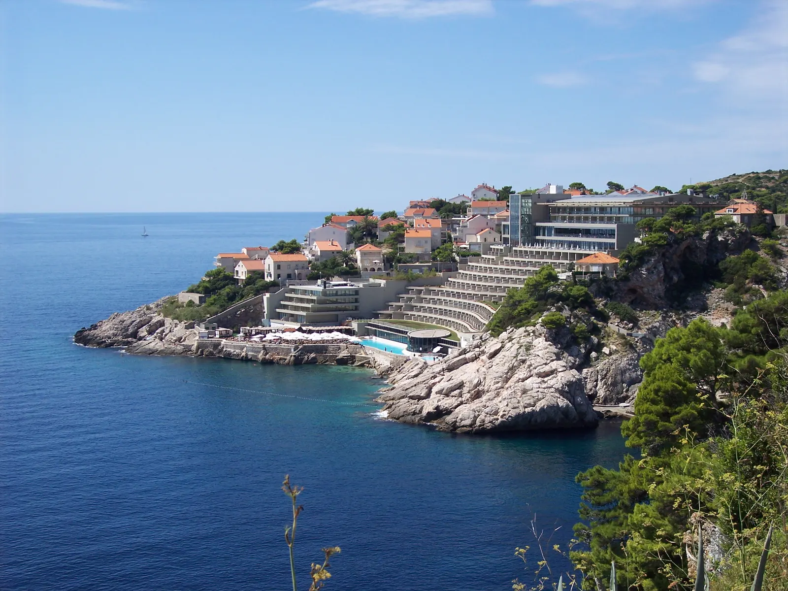 Terrasvormig hotel op de rotsachtige kust bij Dubrovnik met blauwe Adriatische Zee en groene heuvels
