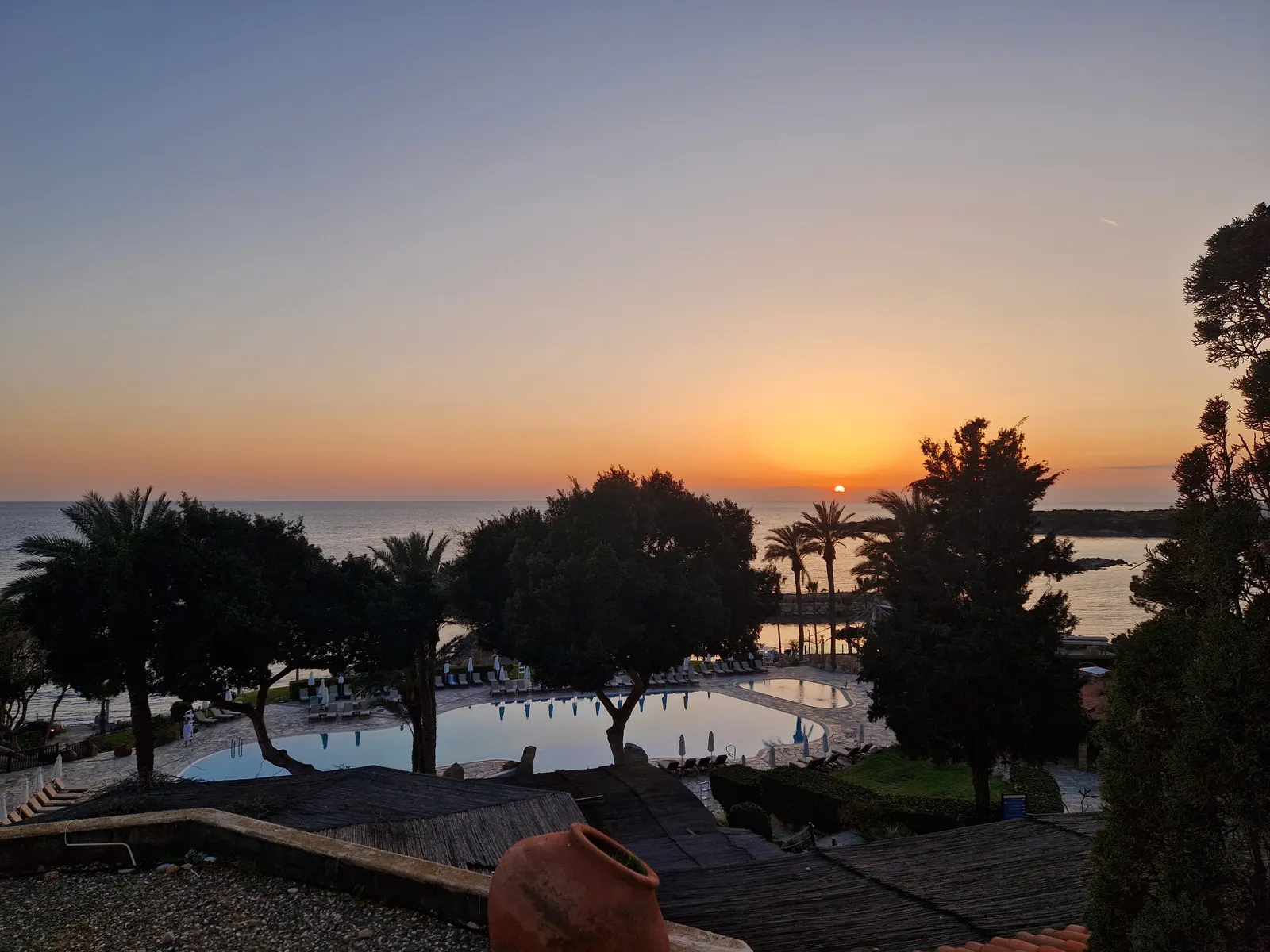 Zonsondergang boven zee gezien vanaf een resort met zwembad en palmbomen bij Coral Bay