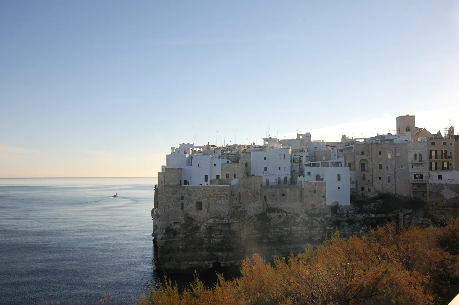 Witte huizen van Polignano a Mare op steile kliffen boven de Adriatische Zee bij zonsondergang