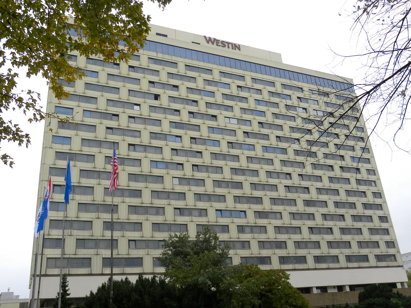 Hoge gevel van hotel The Westin Zagreb met logo bovenaan en vlaggen voor de ingang