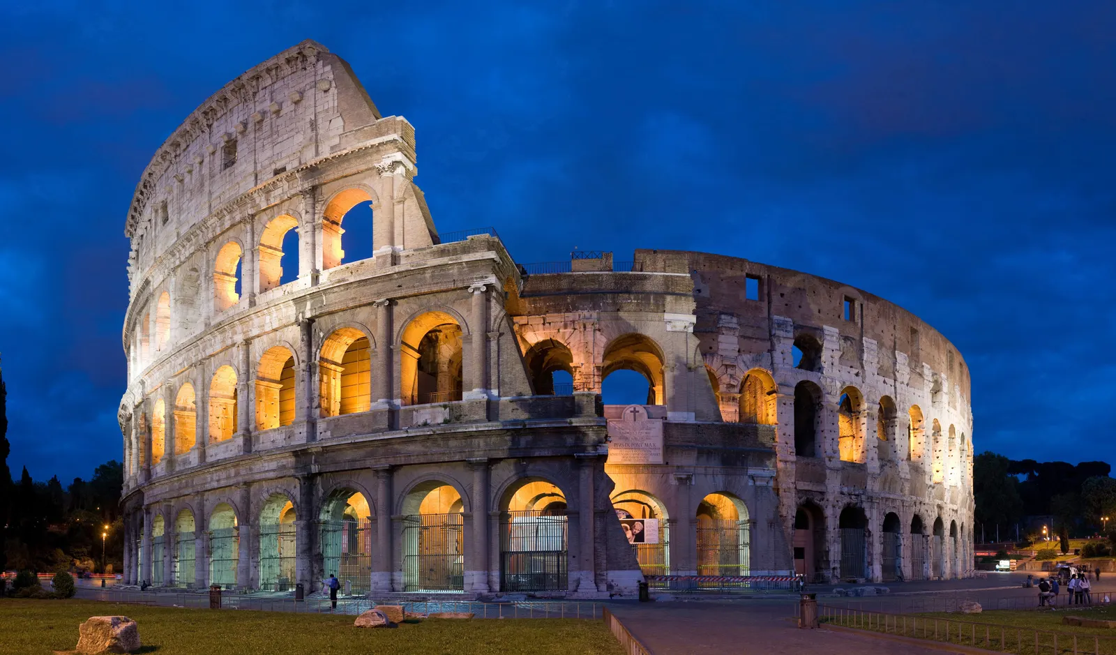 Het verlichte Colosseum in Rome bij avondschemering onder een donkerblauwe lucht