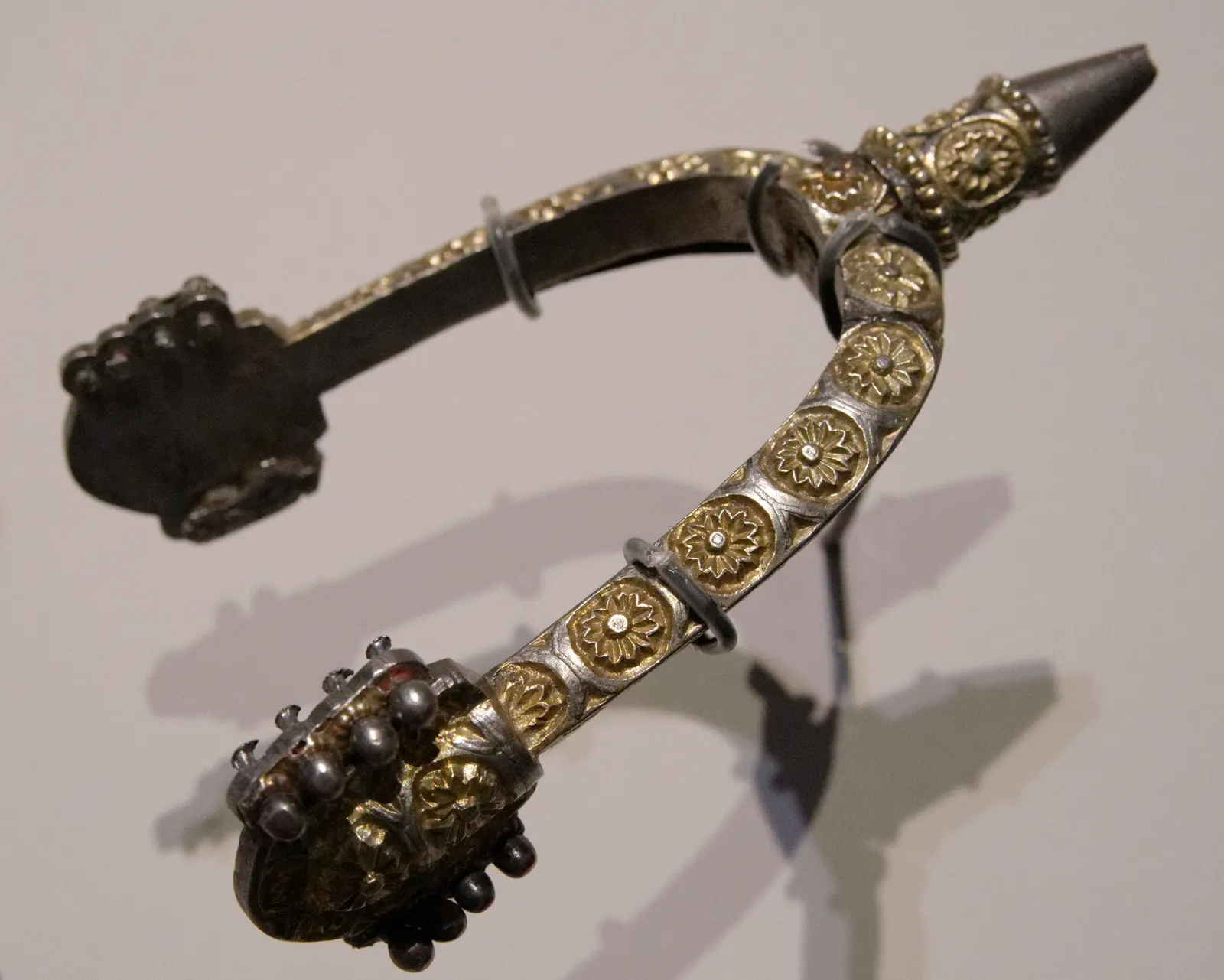 Middeleeuwse vergulde spoor met rozetversiering in een vitrine van het archeologisch museum