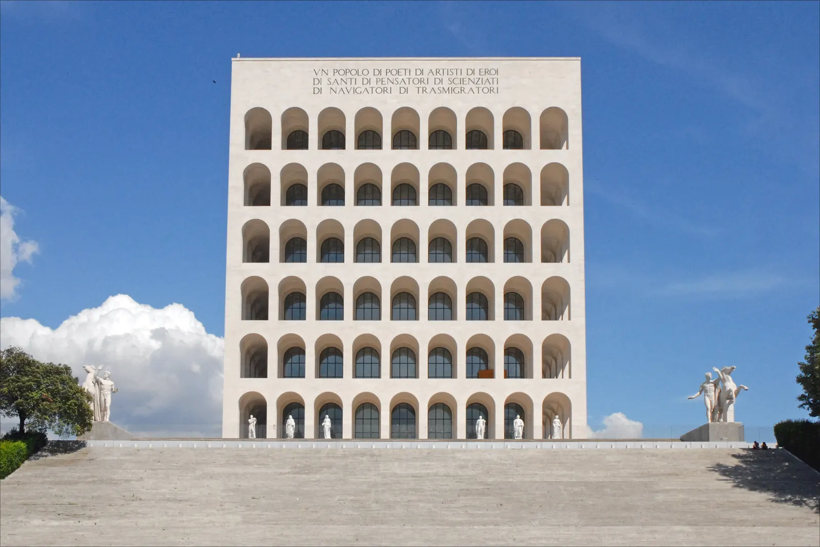 Witte façade van het Palazzo della Civiltà Italiana met bogenrijen, trappen en beelden onder blauwe lucht