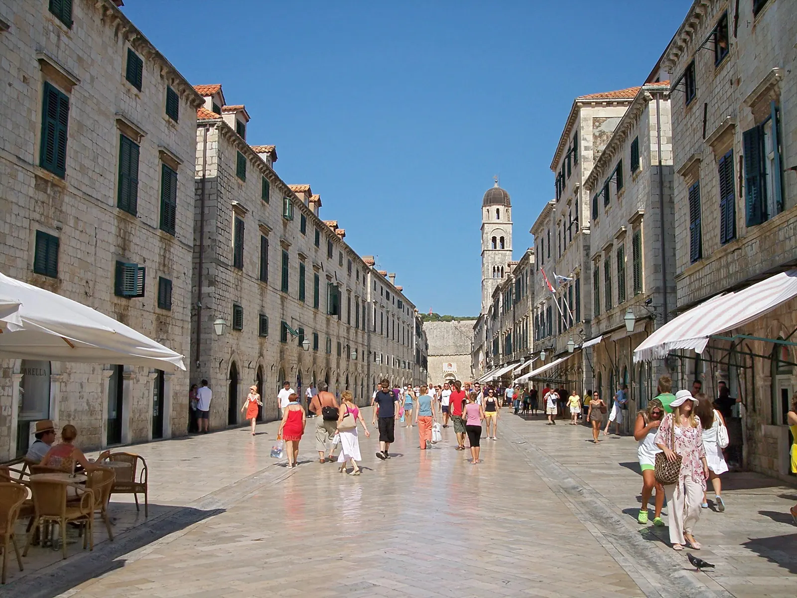 De zonnige Stradun in Dubrovnik met glanzende kalkstenen bestrating, stenen gevels en de klokkentoren van het Franciscanenklooster