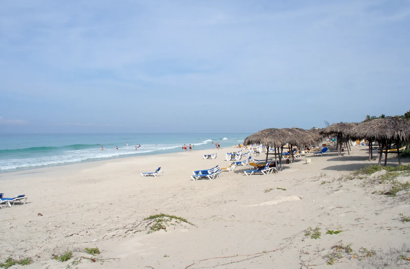 Wit zandstrand van Varadero met ligbedden, rieten parasols en turquoise zee onder een blauwe lucht