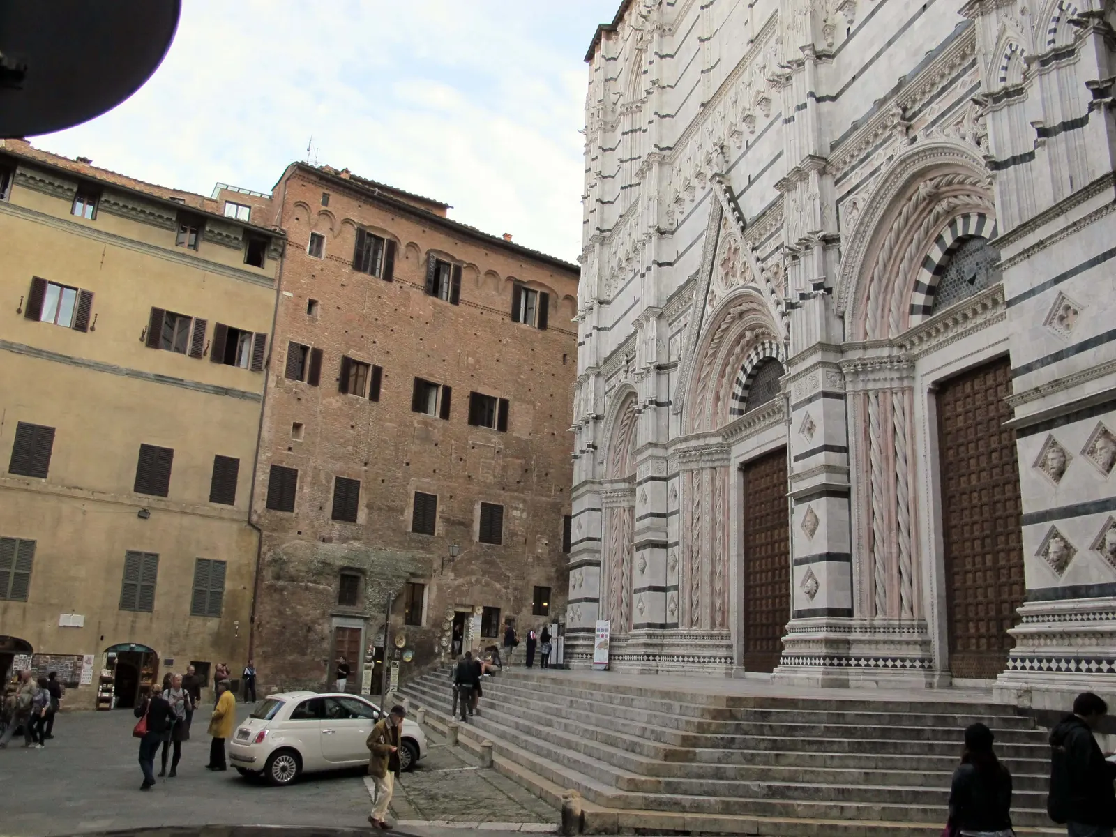 Gotische marmeren gevel van de doopkapel van Siena met trappen en houten deuren aan Piazza San Giovanni