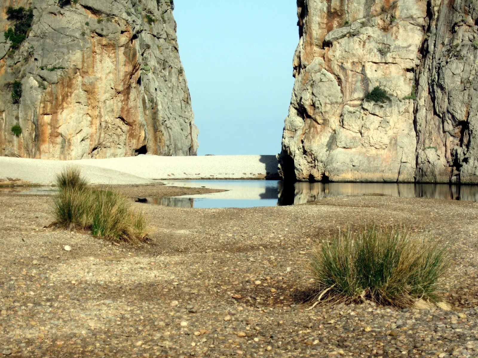 Hoge rotswanden van de Torrent de Pareis-kloof bij Sa Calobra met kiezelstrand en water