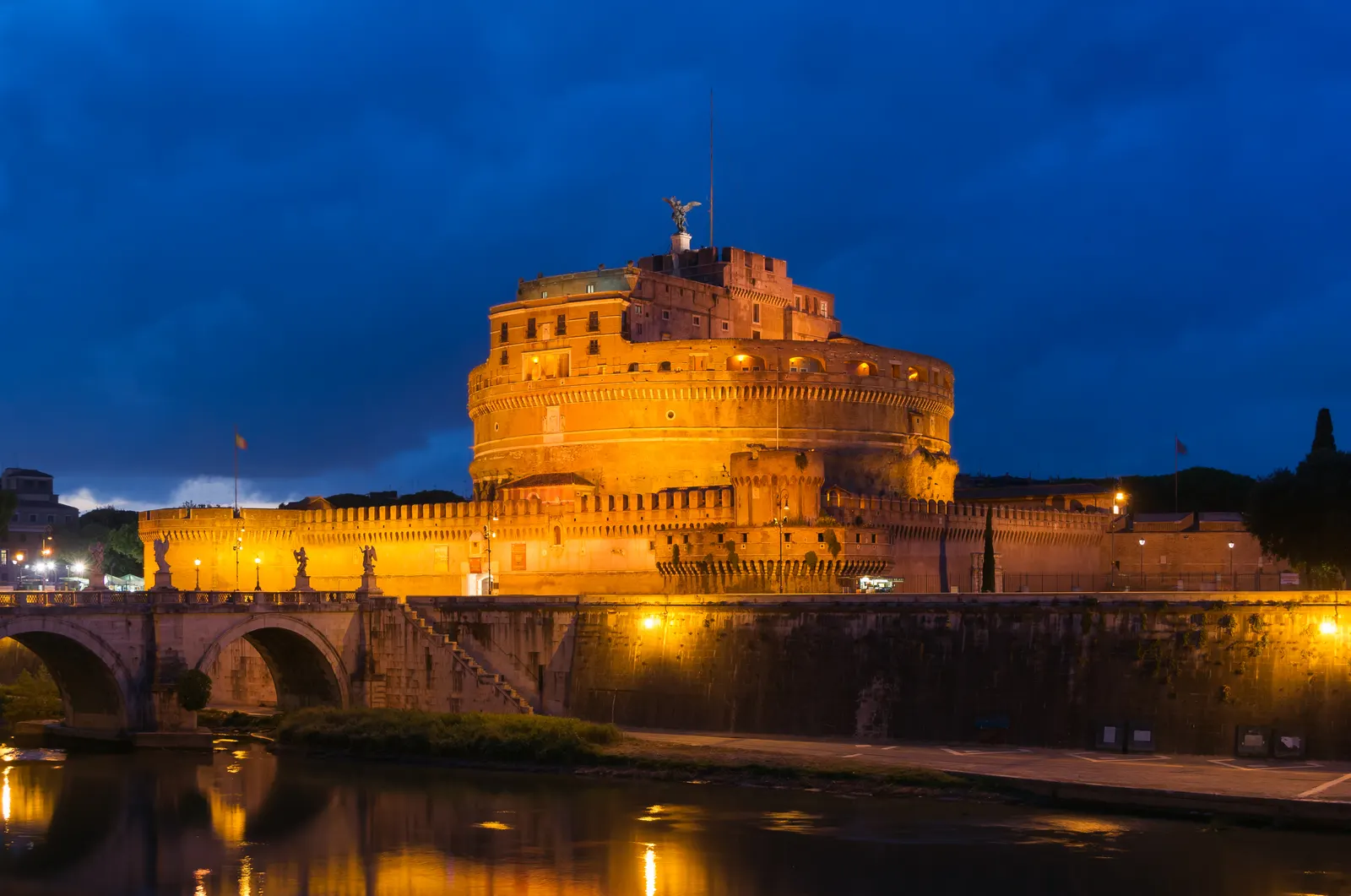 Verlicht Castel Sant'Angelo bij nacht met de Ponte Sant'Angelo en weerspiegeling in de Tiber