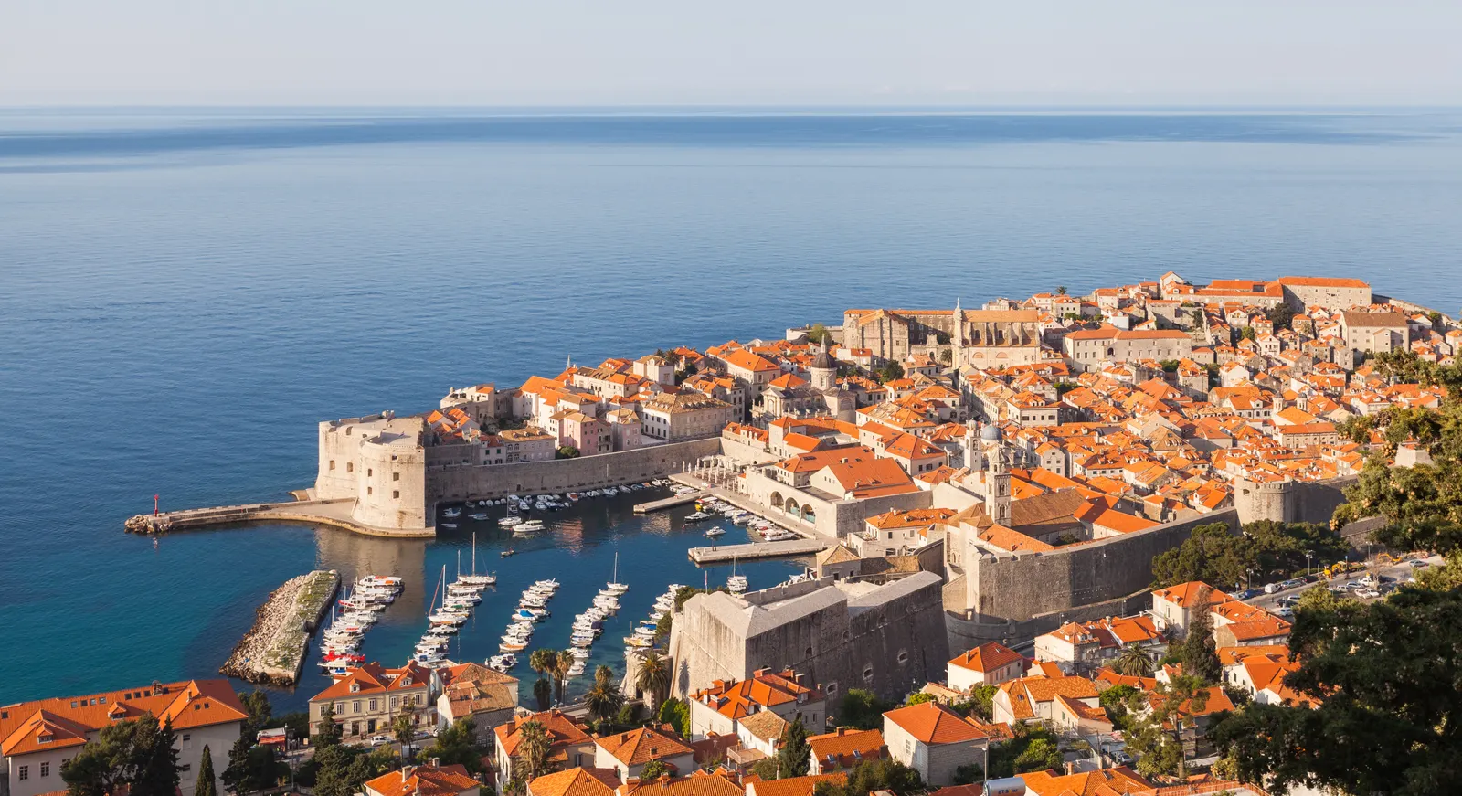 Uitzicht op de ommuurde oude stad van Dubrovnik met oude haven, oranje daken en de blauwe Adriatische Zee