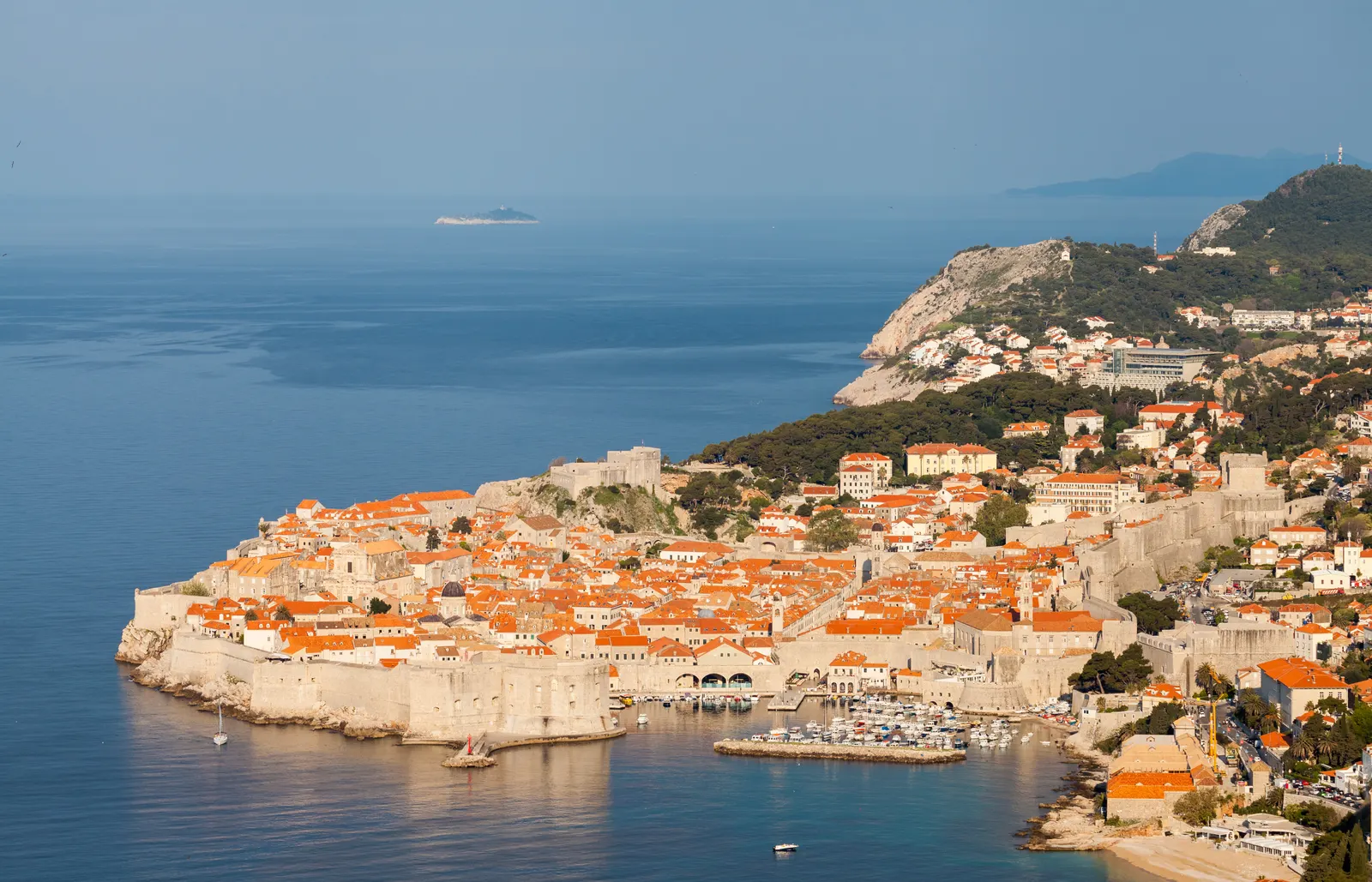 Ommuurde oude stad van Dubrovnik met oranje daken aan de blauwe Adriatische Zee in warm avondlicht