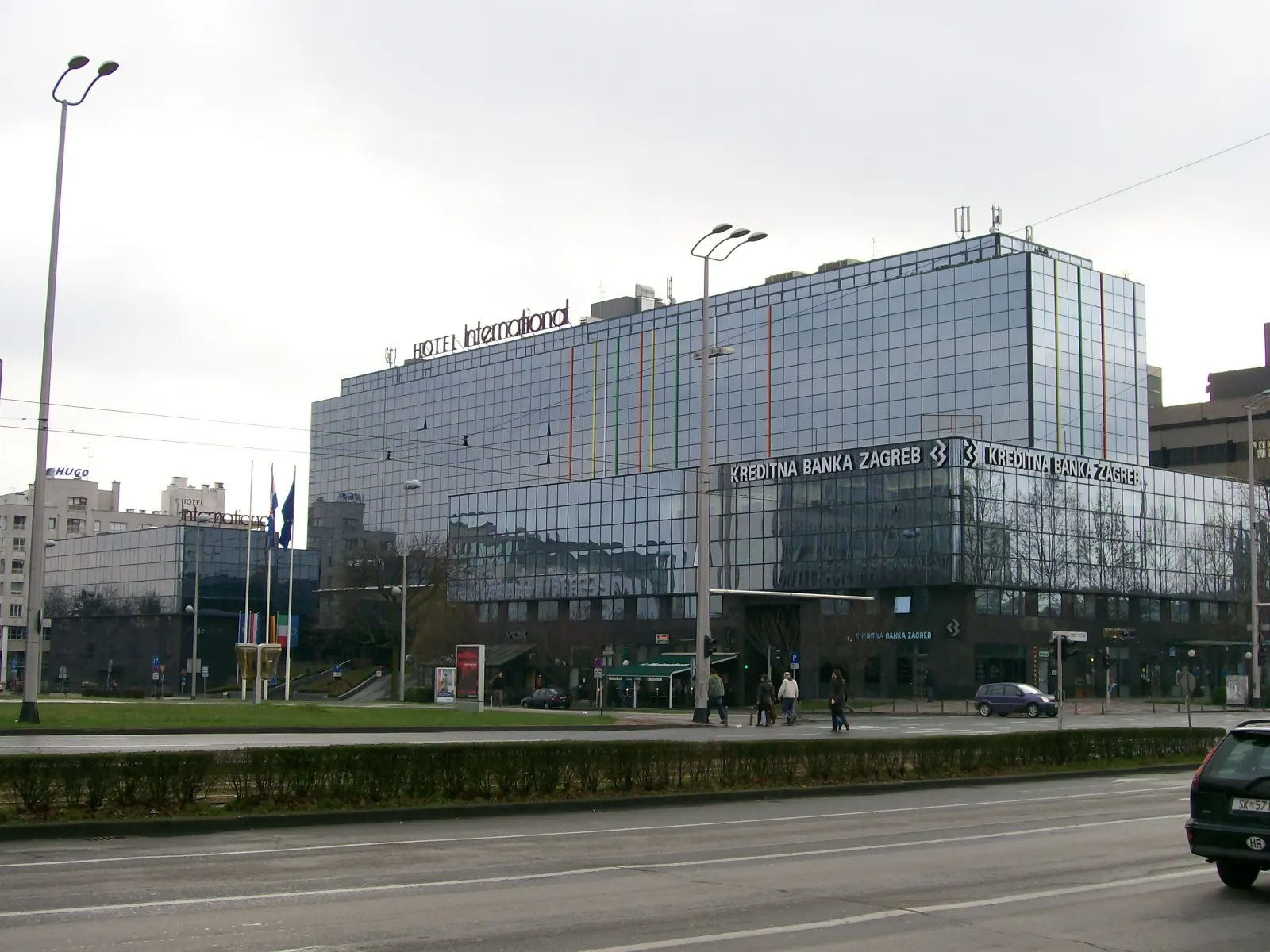 Glazen gevel van Hotel International in Zagreb met hotelnaam op het dak, gezien vanaf een brede straat