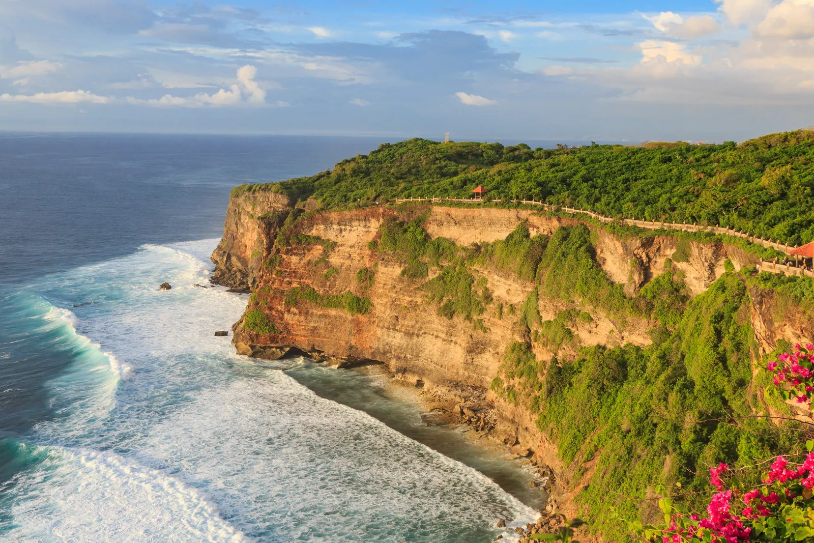Steile kalkstenen kliffen van Uluwatu met groene begroeiing boven de turquoise oceaan en branding